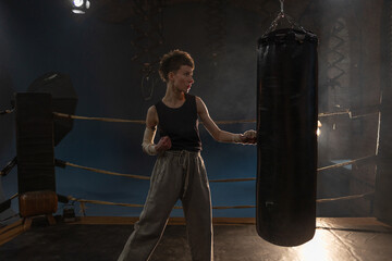 Female boxer training in cinematic gym lighting, powerful punch on bag with colorful dynamic lights