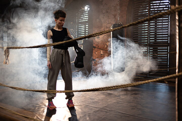 A woman in a boxing ring, wrapping an elastic bandage around her arms, preparing for boxing...