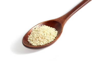 On a white background lies a wooden spoon with sesame seeds.	