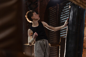 Short-haired boxer pausing workout, leaning on ring ropes with cinematic intensity