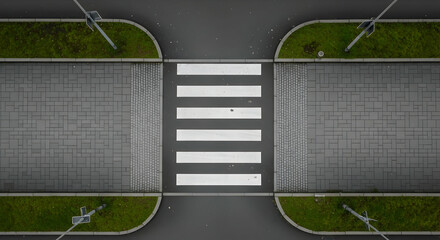Aerial view of a zebra crossing, concrete pavements, grass and street lights showcasing modern urban design and safety features