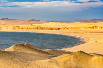 View of the arid desert landscape meeting the deep blue Pacific Ocean at Paracas National Reserve...