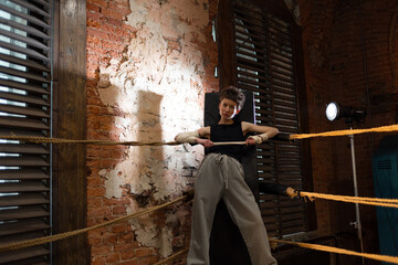 pause between workouts in the corner of the ring. A woman is leaning on a corner stand, a boxing...