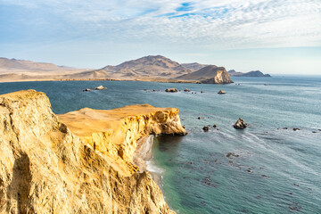 Coastal cliffs and the desert dunes in Paracas National Reserve, Peru. Dramatic landscape with El Playon beach in the distance.