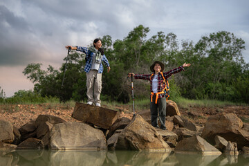 Fototapeta premium Two people standing on a rock near a body of water. One of them is wearing a backpack