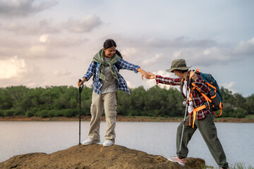 Naklejka premium A man and a woman are standing on a rock near a lake. The woman is holding the man's arm