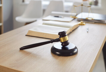 Close up photo of judge's workplace with gavel and scales on wooden table. Empty modern interior of...