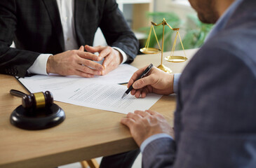 Client signing contract during office meeting with lawyer or attorney, focusing on agreement and...