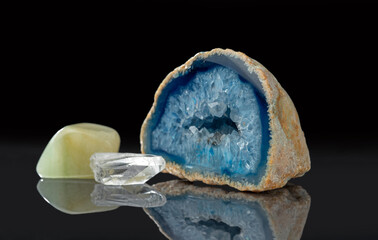 Nephrite, clear quartz crystal, blue agate geode with quartz crystals on a black mirror background.