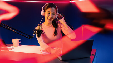 Smiling creative young beautiful Asian influencer talking in channel with positive podcast speech...