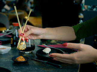 Fototapeta premium A woman is eating sushi with chopsticks