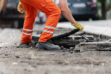 Construction worker removes debris from road during repair in urban area on a sunny day