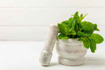 Fresh mint with mortar and pestle on wooden background. Melissa leaves. Healing herbs green mint...