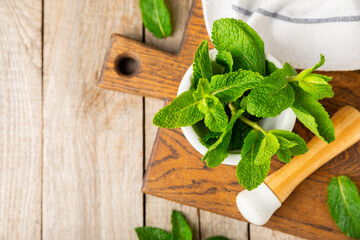 Fresh mint with mortar and pestle on wooden background. Melissa leaves. Healing herbs green mint...