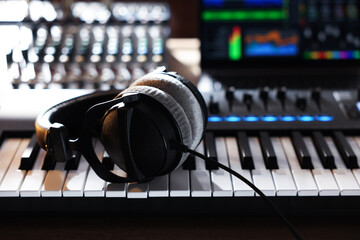 MIDI keyboard with headphones, dj mixer and laptop on table, closeup