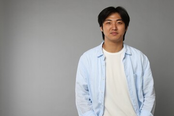 Portrait of handsome Asian man on grey background. Space for text