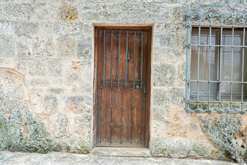 Historic wooden door and barred window in Brihuega, Guadalajara, Spain, showcasing traditional architecture and rustic charm