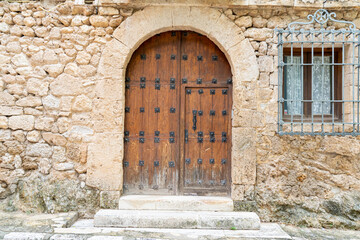 Fototapeta premium Beautiful wooden door in historic stone wall of Brihuega, Castilla-La Mancha, Spain, reflecting traditional architecture