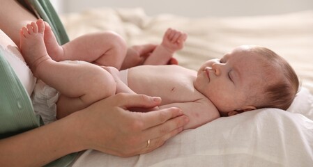 Mother putting her cute newborn baby to sleep at home, closeup