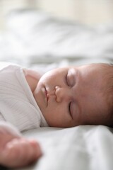 Cute newborn baby sleeping on bed, closeup