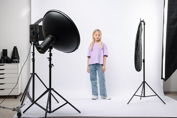 Little girl on white background in photo studio with professional equipment