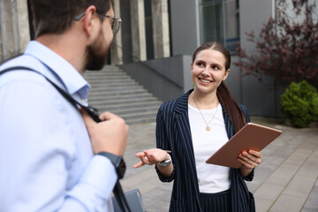 Happy coworkers with tablet near office building