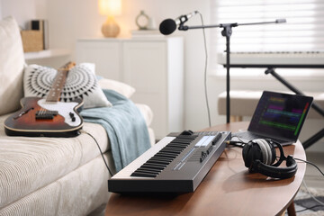 MIDI keyboard, laptop and headphones on wooden table in home studio