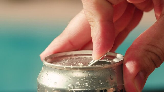 Opening soda or beer can, macro close up of can pull tab opening, watering refreshment, hand open lemonade or juice.