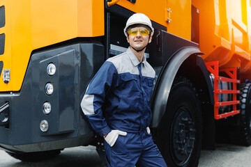 Happy industrial driver man of dump truck sits in cab and works on open pit mine