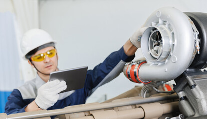 Diagnostics on turbocharged engines of mining truck in garage, Mechanic with tablet computer fix...