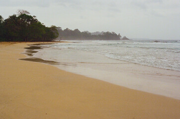Captivating coastal landscape featuring a tranquil sandy beach with gentle waves and lush surrounding vegetation. The serene ambiance evokes peace and connection with nature. Red Frog Beach, Panama