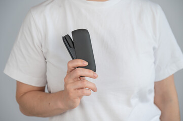 A woman takes a tobacco heating system out of a charger. Electronic cigarette.