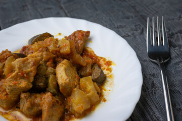 Hearty Homemade Pork and Vegetable Stew on White Plate with Fork on Dark Wood Table