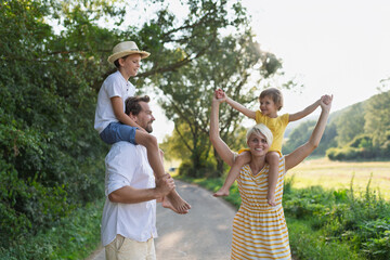 A portrait of young family with small children in sunny summer nature.