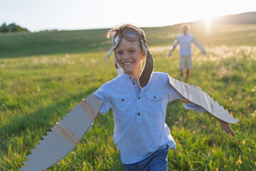 Child playing aviator in nature with wings and goggles.