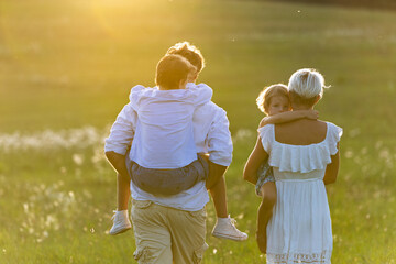 Rear view of family with two kids on walk in summer nature.