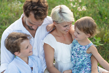 Fototapeta premium Young family enjoying peaceful summer evening outdoors in green summer nature