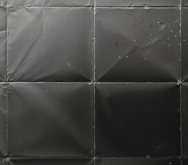 A monochrome (black and white) photograph of a textured paper surface, displaying prominent fold lines.