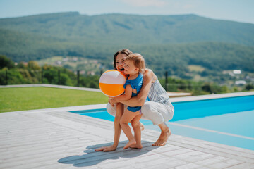 Little child and mother enjoying outdoor playtime with inflatable ball