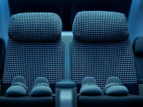 Two spacious airline seats with stylish houndstooth pattern are accompanied by soft slippers, inviting passengers to relax in comfort during a nighttime journey.