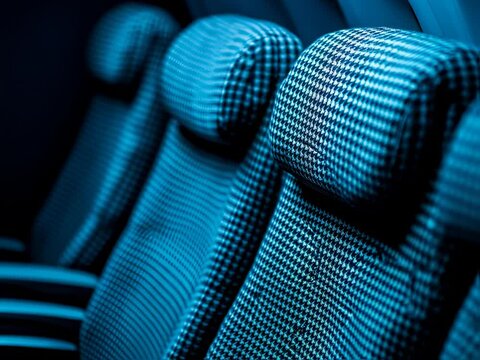 Two spacious airline seats with stylish houndstooth pattern are accompanied by soft slippers, inviting passengers to relax in comfort during a nighttime journey.