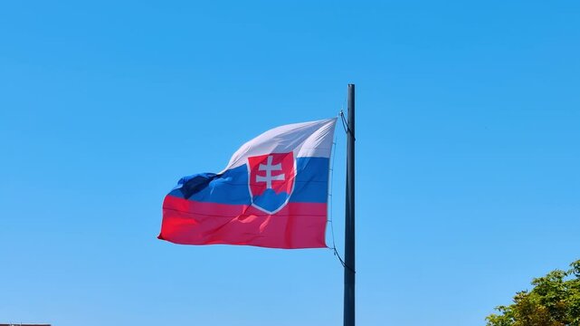 Flag of Slovakia waving in the wind. Slovak flag at the backdrop of blue clear sky.