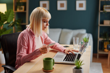 Young woman working from home is making an online payment using her credit card