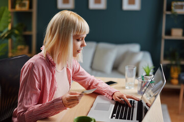 Focused freelancer making online payment with credit card at home office