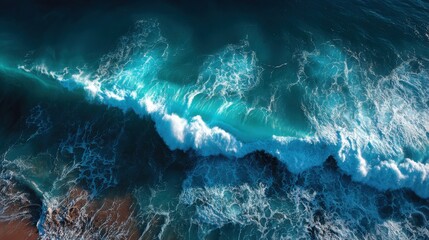 Bright blue waves roll into the rocky shoreline under a clear sky. The dynamic ocean movement creates foamy white tops, showcasing the power and beauty of the sea during daylight.
