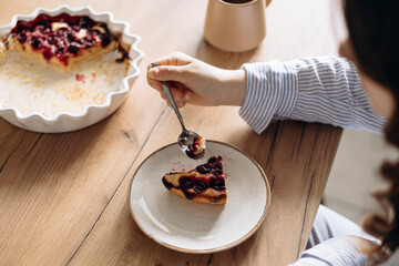 Woman eating homemade cherry pie with coffee at home, close-up.