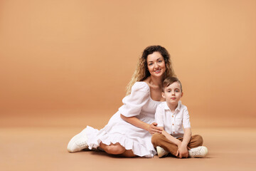 Family. Happy mother and her son posing on beige background. Space for text