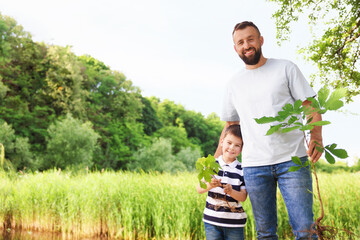 Father and his son planting tree outdoors, space for text