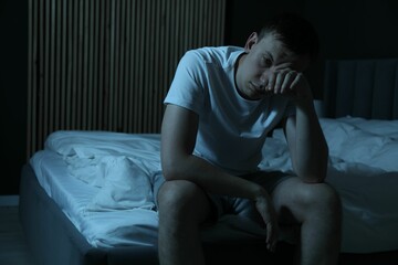 Frustrated man suffering from insomnia on bed indoors, space for text