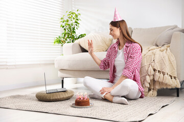 Birthday celebration. Happy woman with tasty cake having video call via laptop at home